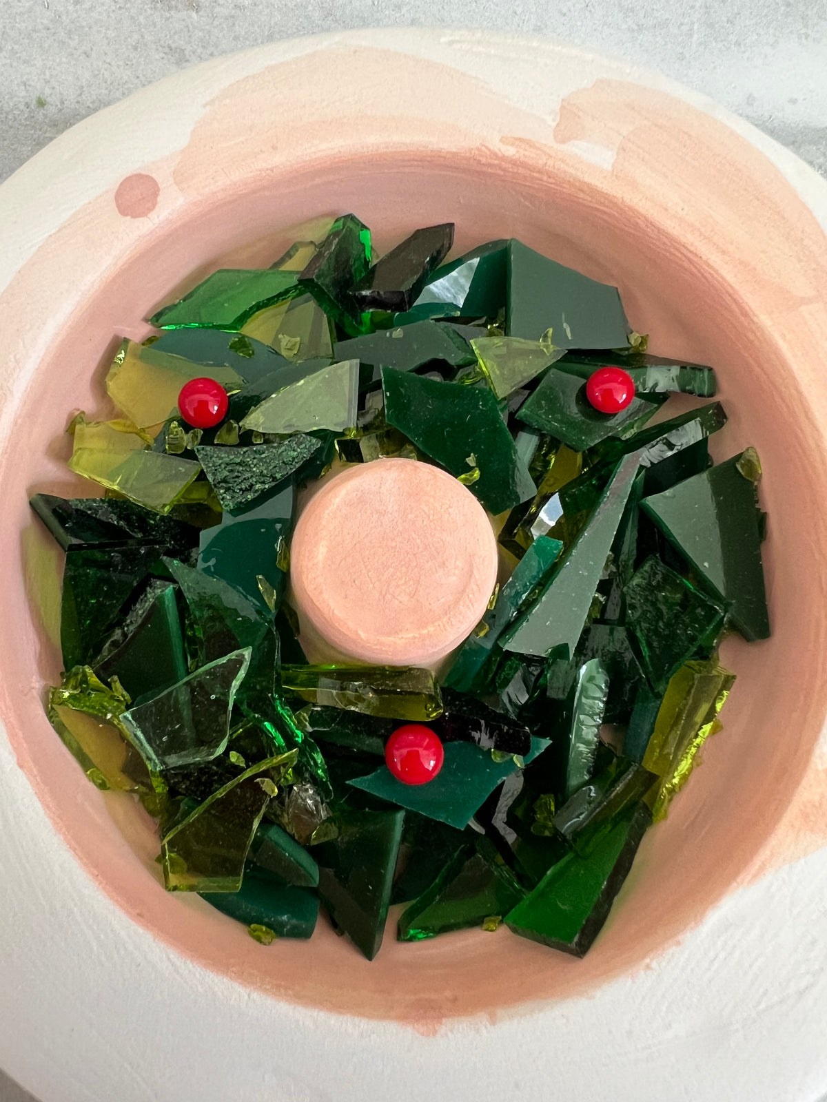 Photo of a fired green fused glass wreath with red berry accents in its casting mold